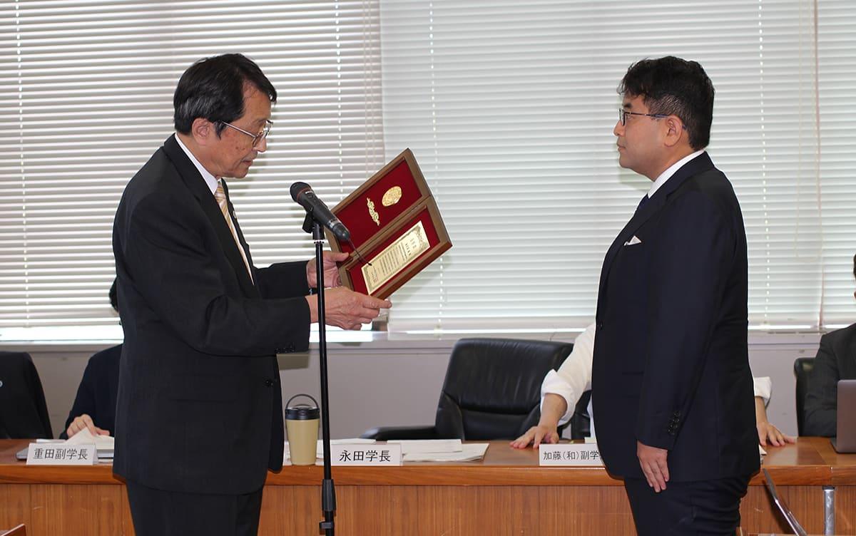 永田学長から表彰楯を受け取る海老原准教授