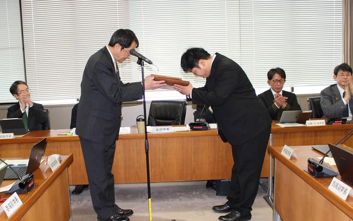 写真：永田学長から表彰楯を授与される宮川准教授