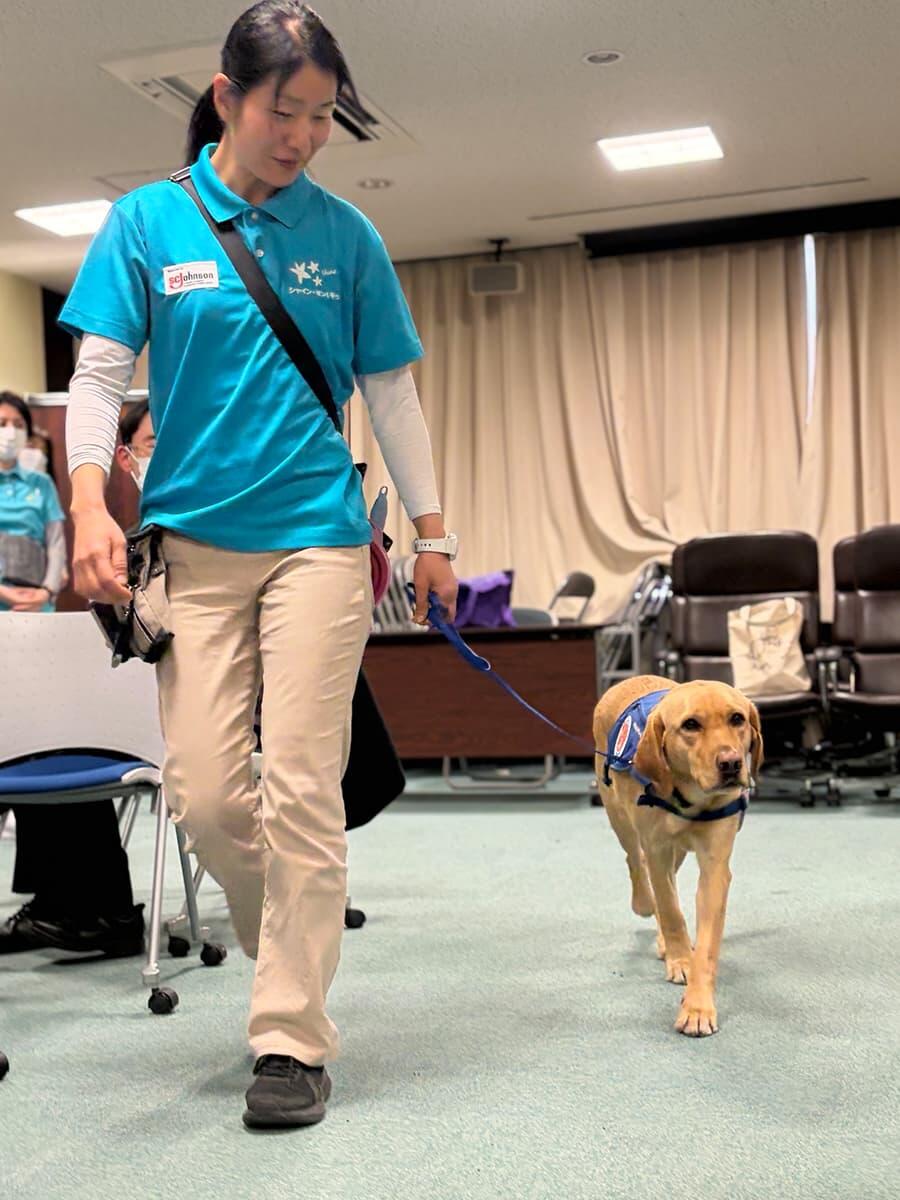 ファシリティドッグとハンドラーが歩いている写真